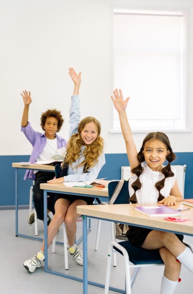 Engaged students in a diverse classroom participate actively, raising hands with enthusiasm.