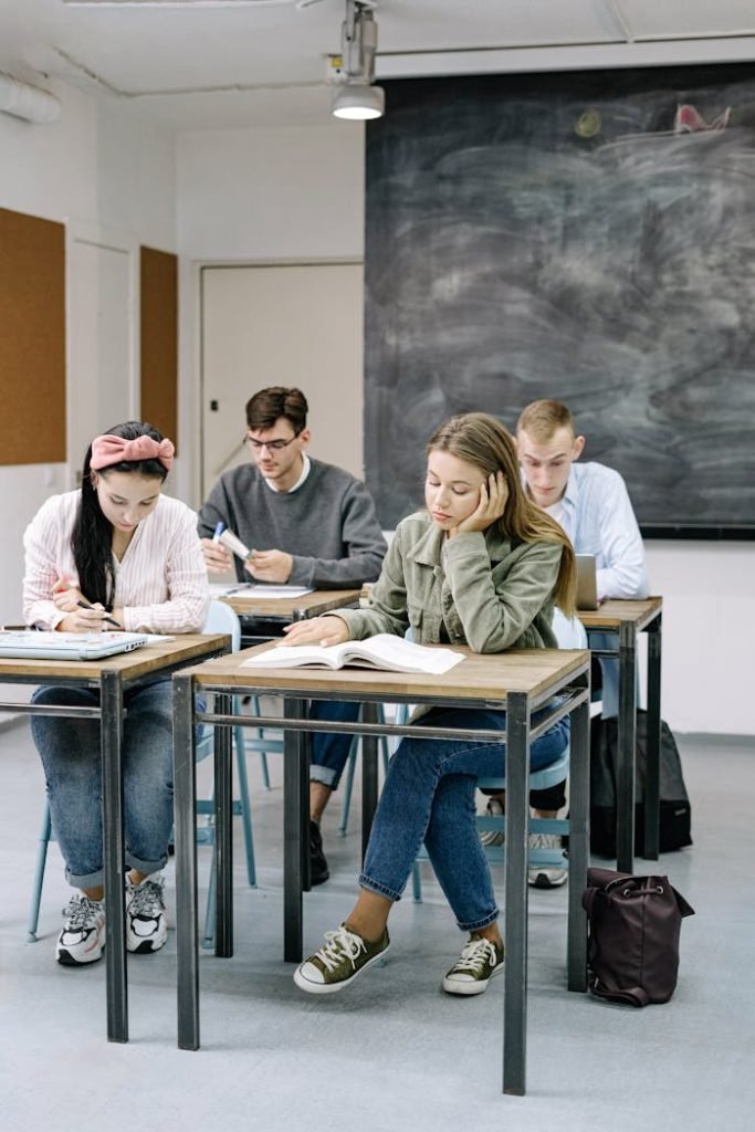 A group of teenagers focusing on studies in a classroom with a blackboard.